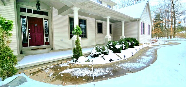 snow covered property entrance with a porch