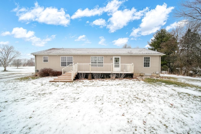 snow covered rear of property with a deck