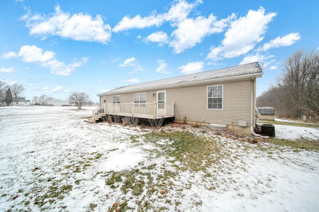 snow covered house featuring a deck and central AC