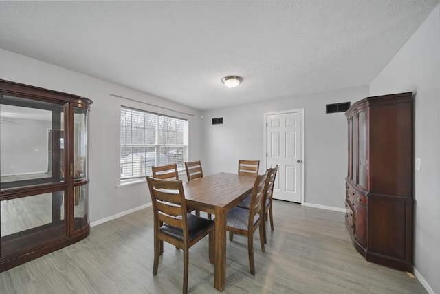 dining space featuring a textured ceiling and light hardwood / wood-style flooring