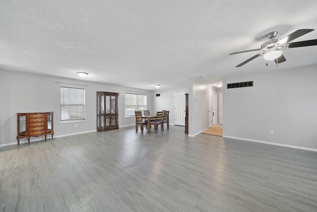 unfurnished living room featuring ceiling fan, hardwood / wood-style floors, and a textured ceiling