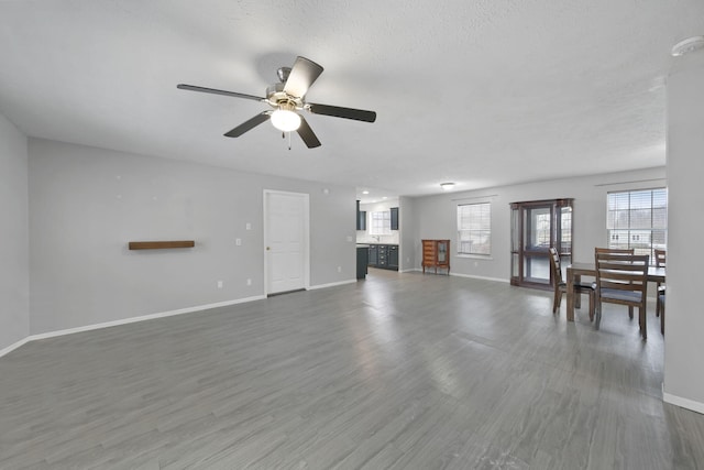 unfurnished living room with a textured ceiling, ceiling fan, and dark hardwood / wood-style flooring