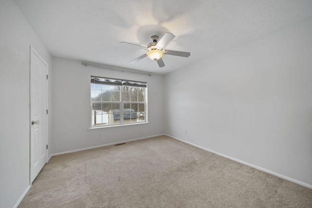 spare room with ceiling fan, a textured ceiling, and light carpet