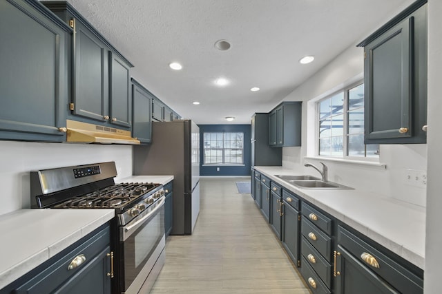 kitchen featuring sink, a textured ceiling, and stainless steel gas range