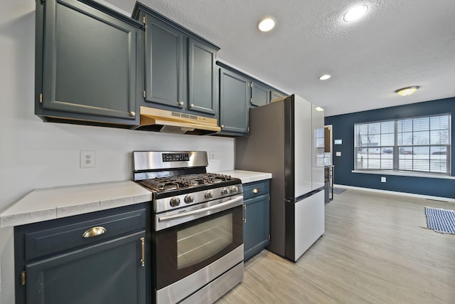 kitchen featuring light wood-type flooring, appliances with stainless steel finishes, and a textured ceiling