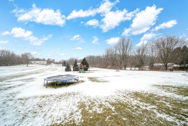 yard layered in snow with a trampoline