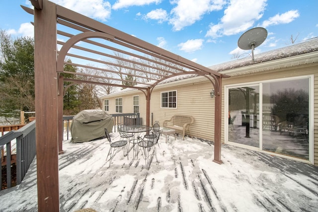 snow covered deck featuring area for grilling and a pergola