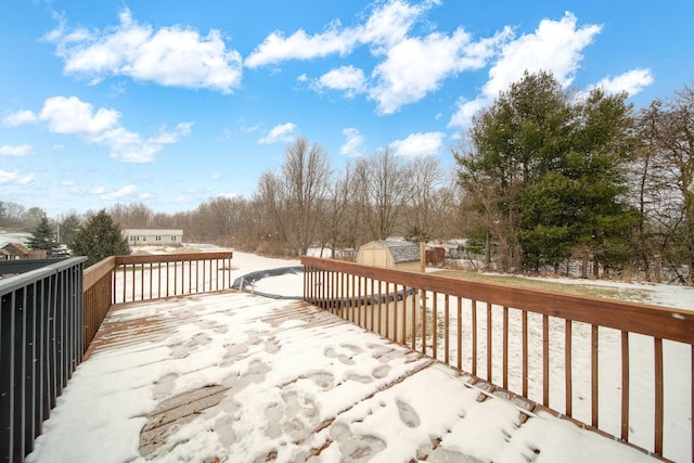 snow covered deck featuring a shed