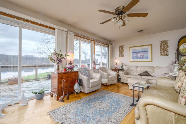 living room featuring ceiling fan, hardwood / wood-style floors, and a water view