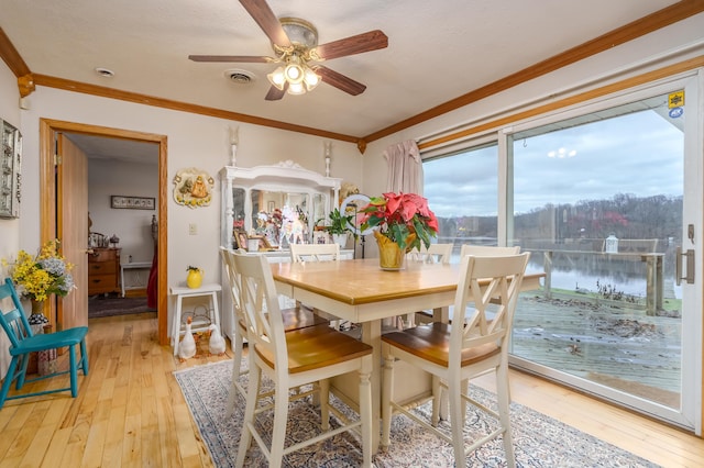 dining room featuring a textured ceiling, ceiling fan, crown molding, a water view, and light hardwood / wood-style flooring