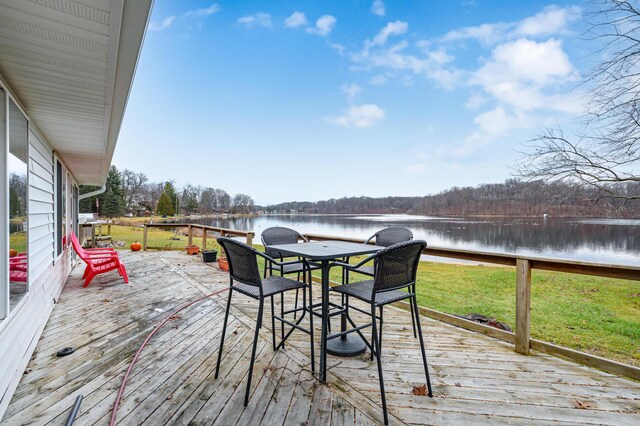 wooden deck featuring a water view and a lawn