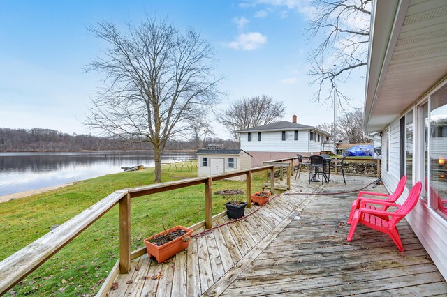 deck with a water view and a lawn