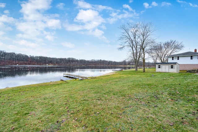 view of yard with a boat dock, a water view, and an outdoor structure