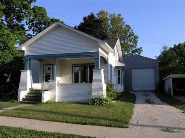 bungalow featuring an outbuilding, a porch, a garage, and a front lawn