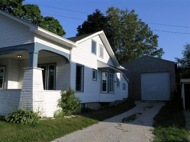 view of property exterior featuring covered porch, an outbuilding, and a garage