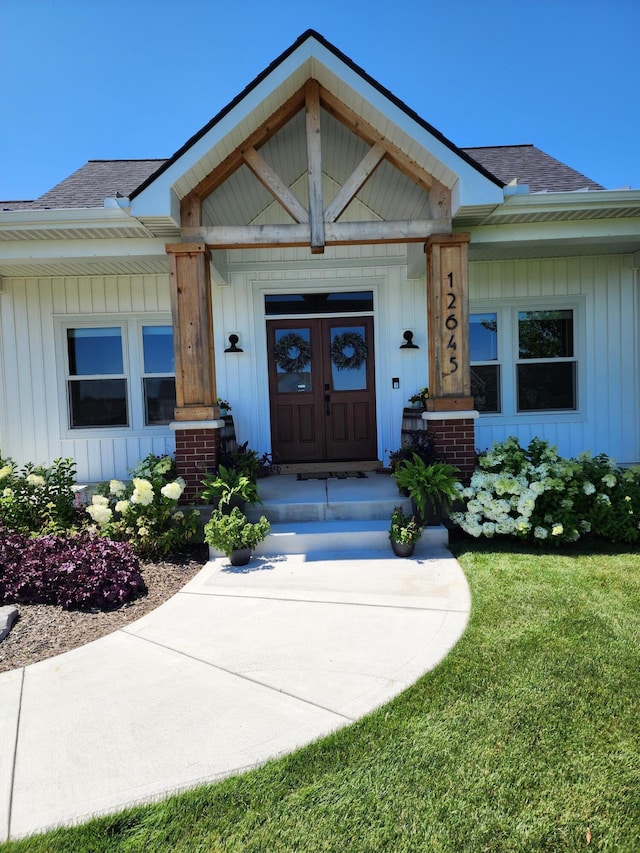 view of exterior entry with french doors, a yard, and a porch