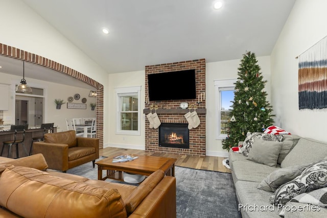 living room featuring hardwood / wood-style flooring, lofted ceiling, and a fireplace