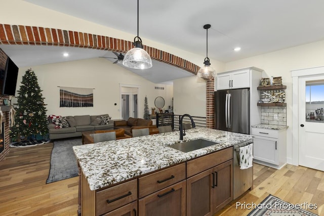 kitchen with sink, stainless steel appliances, pendant lighting, light hardwood / wood-style floors, and white cabinets