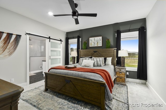 bedroom with a barn door, ceiling fan, and carpet