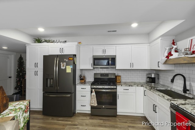 kitchen with stainless steel appliances, white cabinetry, dark hardwood / wood-style floors, and sink