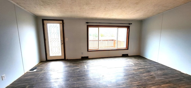 empty room with dark wood-type flooring and a textured ceiling