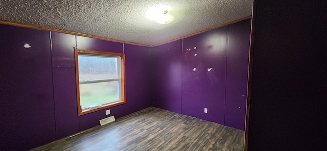 unfurnished room with wood-type flooring, a textured ceiling, and ornamental molding