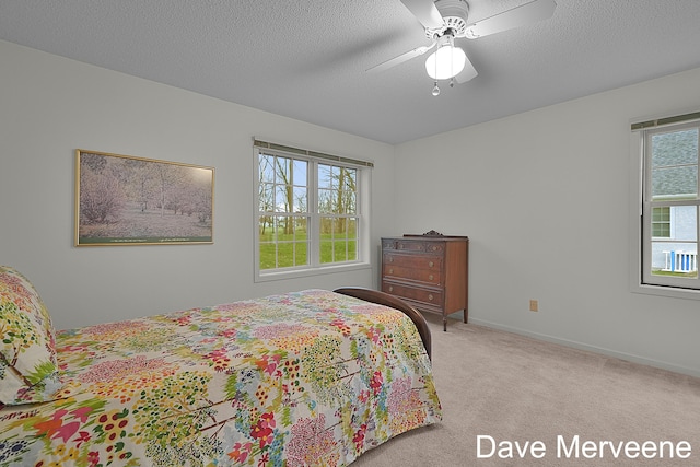 bedroom with a textured ceiling, ceiling fan, light carpet, and multiple windows