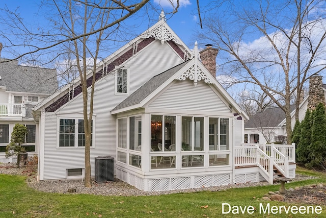 rear view of property with central air condition unit, a lawn, and a sunroom