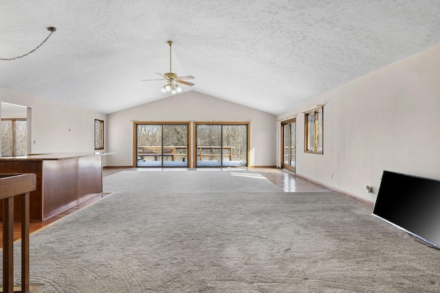 unfurnished living room with ceiling fan, lofted ceiling, light carpet, and a textured ceiling