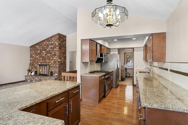 kitchen featuring lofted ceiling, sink, decorative light fixtures, and appliances with stainless steel finishes