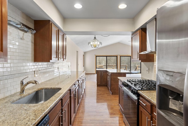 kitchen featuring sink, hanging light fixtures, stainless steel fridge, range with gas stovetop, and light stone countertops