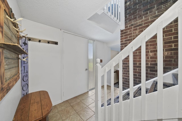 tiled foyer entrance featuring brick wall and a textured ceiling