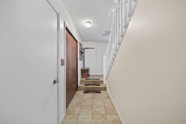 hall featuring light tile patterned floors and a textured ceiling