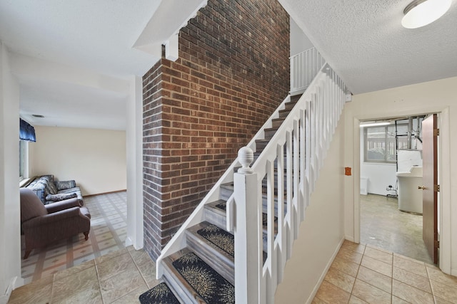 stairs with tile patterned flooring, a textured ceiling, vaulted ceiling, and brick wall