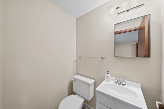 bathroom with vanity, toilet, and a textured ceiling