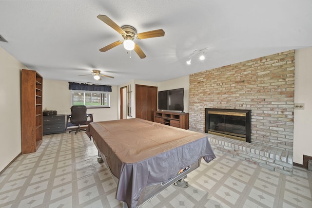 recreation room featuring a brick fireplace, ceiling fan, a textured ceiling, and pool table