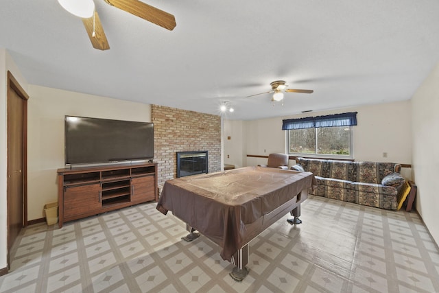 rec room with a textured ceiling, a brick fireplace, ceiling fan, and billiards