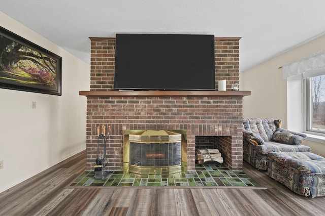 room details featuring wood-type flooring, a textured ceiling, and a brick fireplace