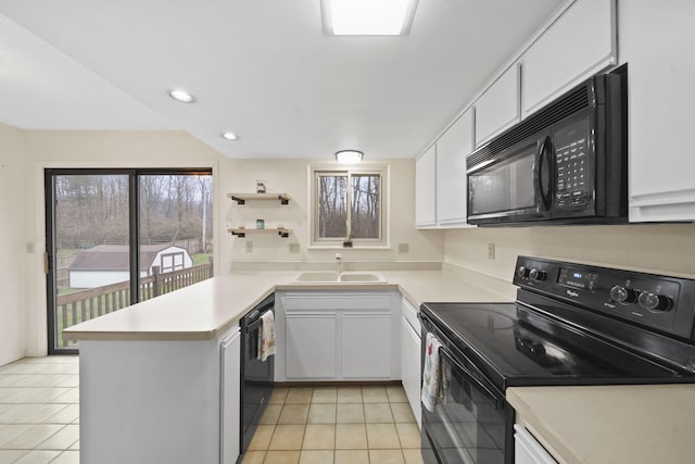 kitchen featuring kitchen peninsula, light tile patterned flooring, white cabinets, and black appliances