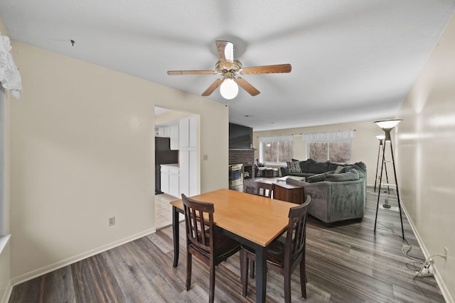 dining room featuring dark hardwood / wood-style floors, ceiling fan, and a fireplace