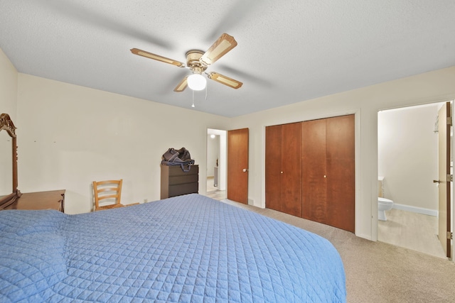 bedroom featuring ensuite bath, ceiling fan, light colored carpet, a textured ceiling, and a closet