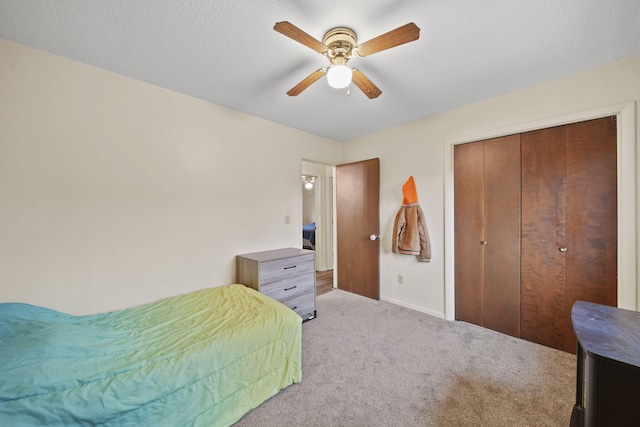 carpeted bedroom with a textured ceiling, a closet, and ceiling fan