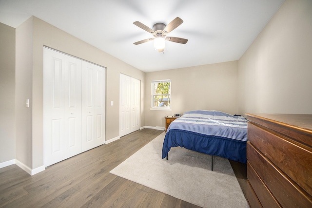 bedroom featuring ceiling fan, two closets, and hardwood / wood-style flooring