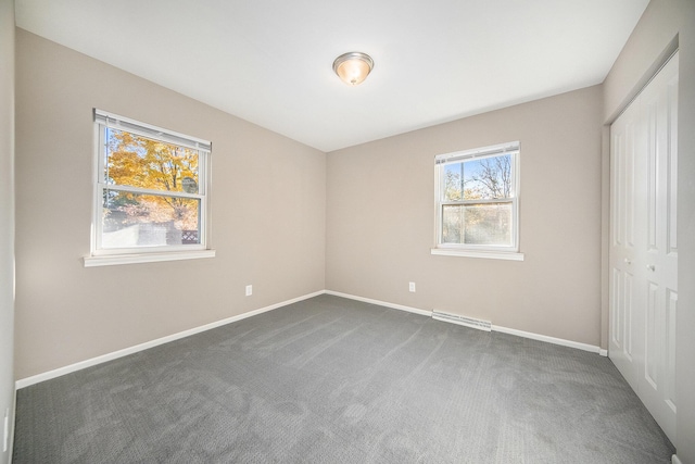 unfurnished bedroom featuring dark carpet and a closet