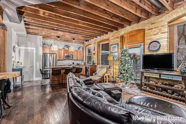 living room with beam ceiling, dark wood-type flooring, and brick wall