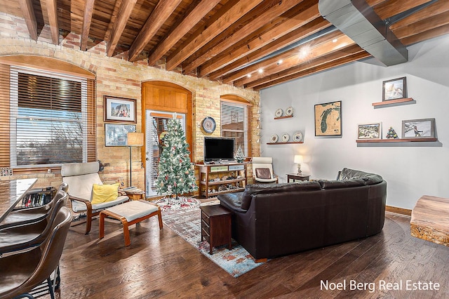 living room with beam ceiling, dark hardwood / wood-style flooring, and brick wall