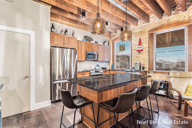 kitchen with a center island, hanging light fixtures, appliances with stainless steel finishes, beamed ceiling, and brick wall