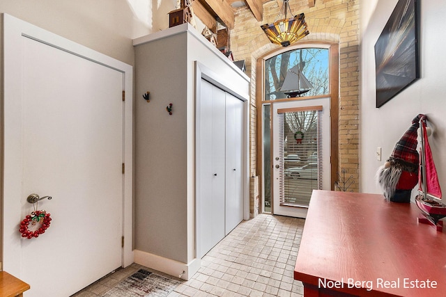 tiled foyer entrance with beamed ceiling and brick wall