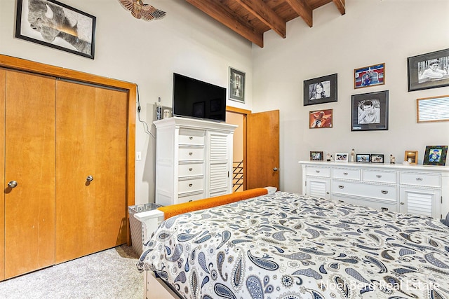 bedroom with beam ceiling, light carpet, a closet, and wooden ceiling