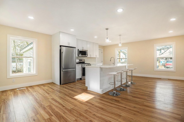 kitchen featuring white cabinets, a wealth of natural light, hanging light fixtures, and appliances with stainless steel finishes